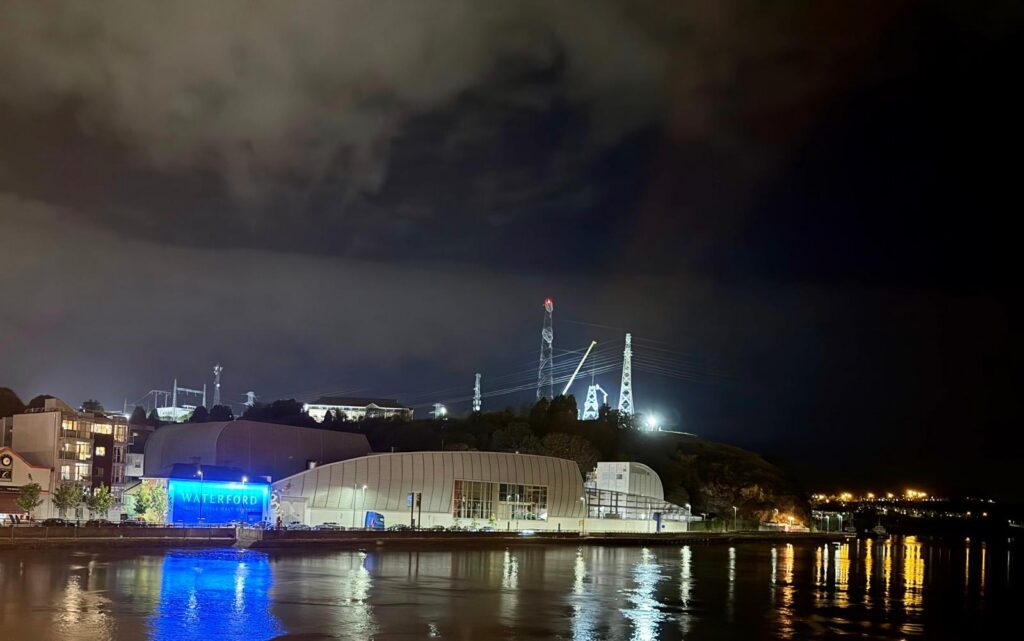 The distillery lit at night, its reflection in the River Suir